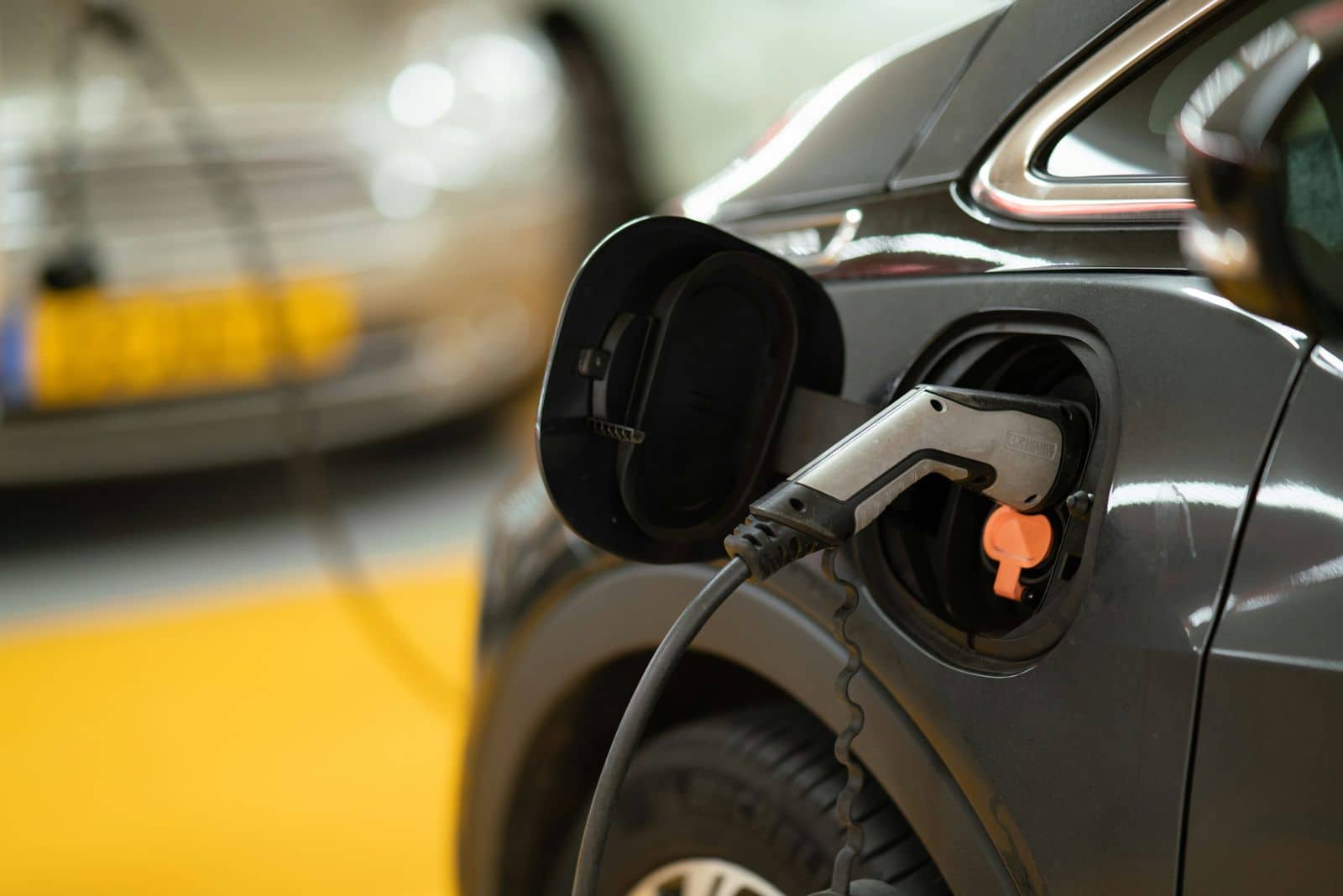 A dark grey car charging in a garage, the cable plugged into its port